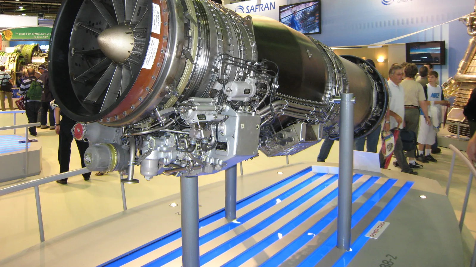 A Safran M88-2 fighter engine displayed on a stand at a Safran exhibition booth, with its fan face and afterburner section visible.
