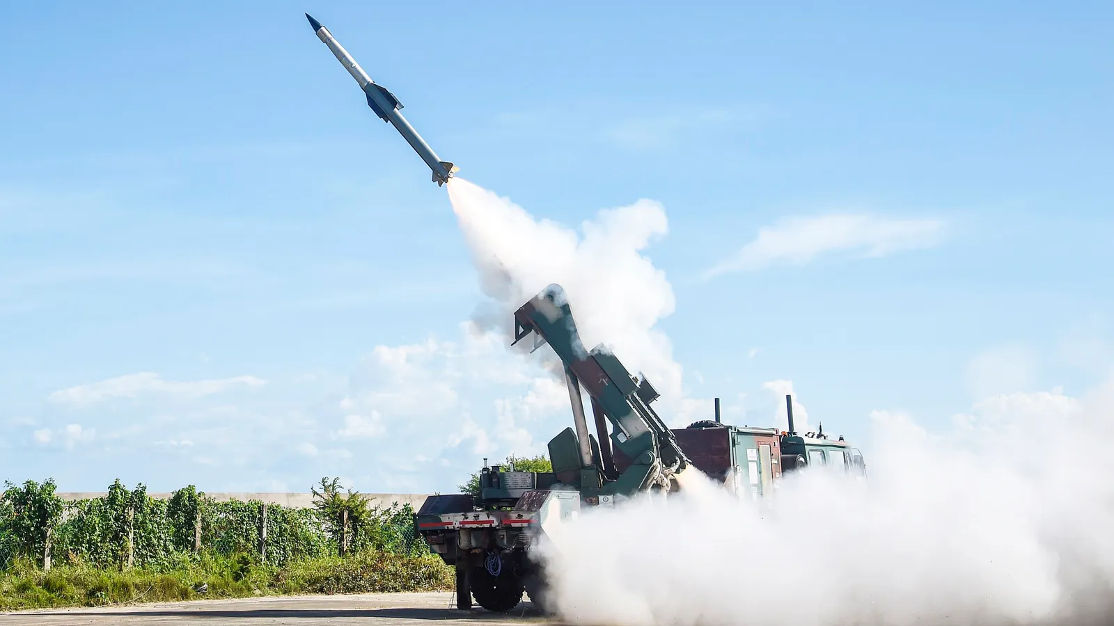 A DRDO Quick Reaction Surface-to-Air Missile lifts off its truck-mounted mobile launcher in a plume of white exhaust against a blue sky during Indian Army flight tests at the Integrated Test Range, Chandipur, Odisha.