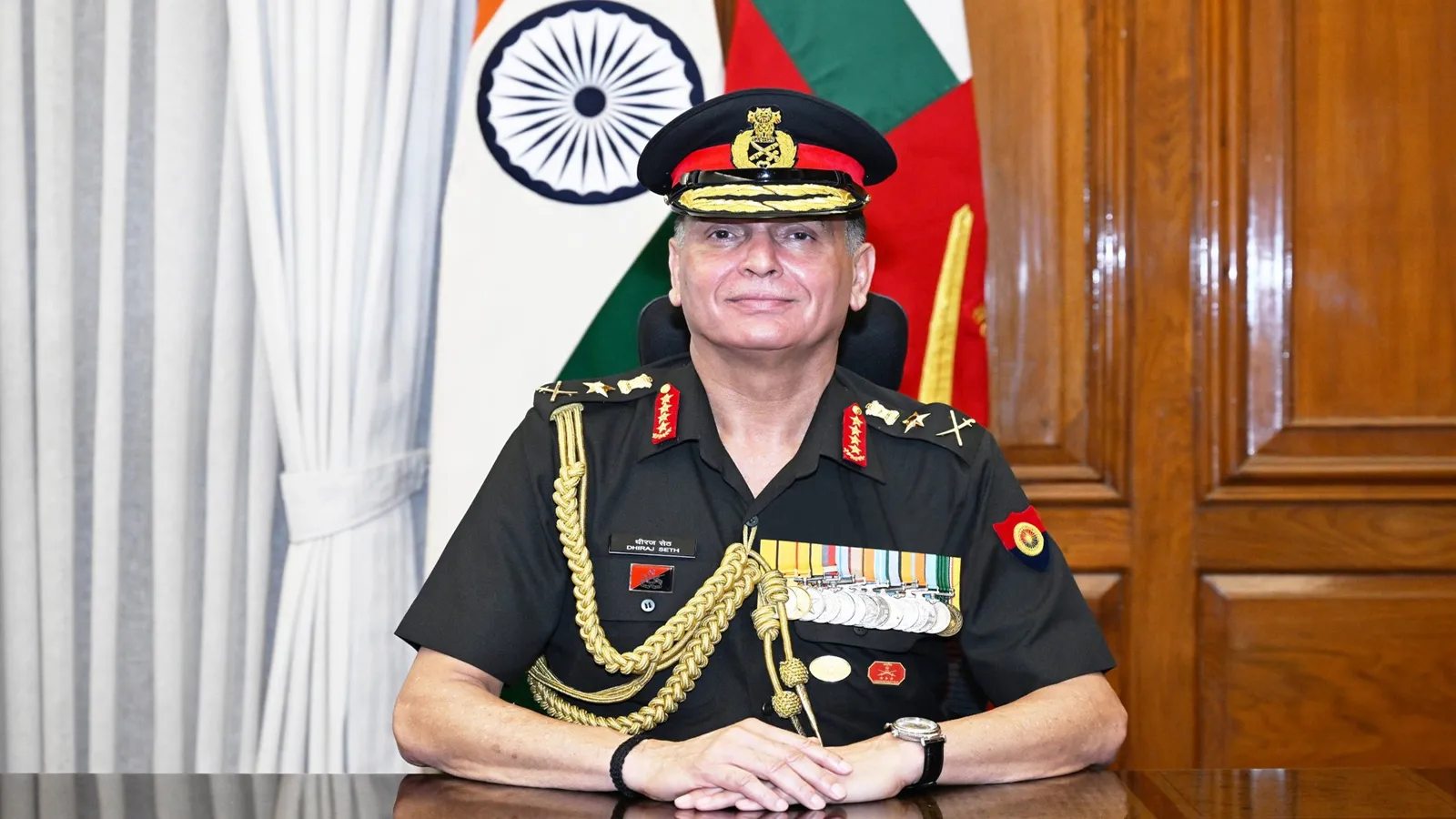General Dhiraj Seth in ceremonial uniform, seated at his desk with the Indian national flag and Army flag behind him after taking charge as Chief of the Army Staff.