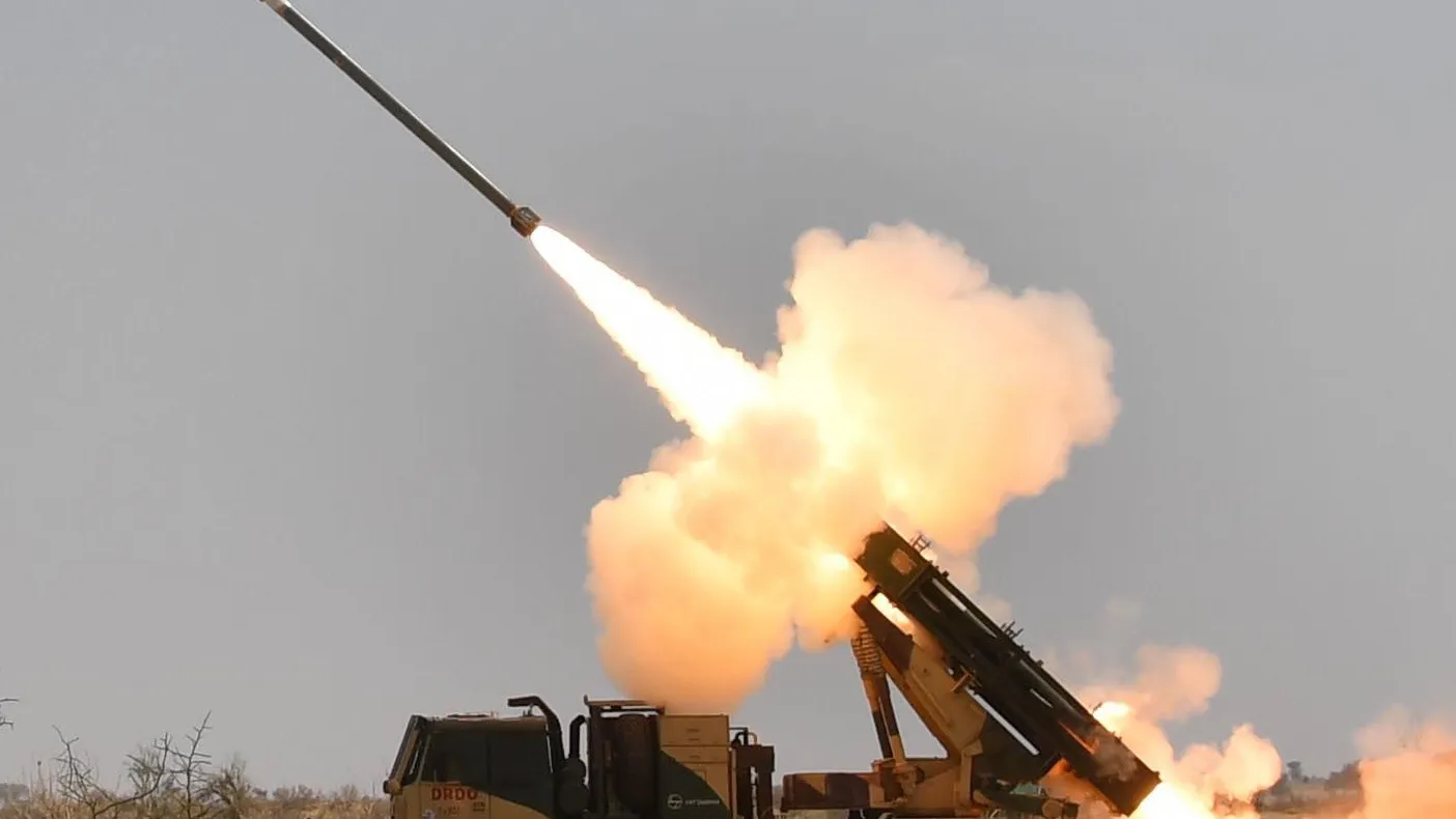 A Guided Pinaka rocket climbs away from a truck-mounted DRDO launcher on a bright exhaust plume during a flight test.