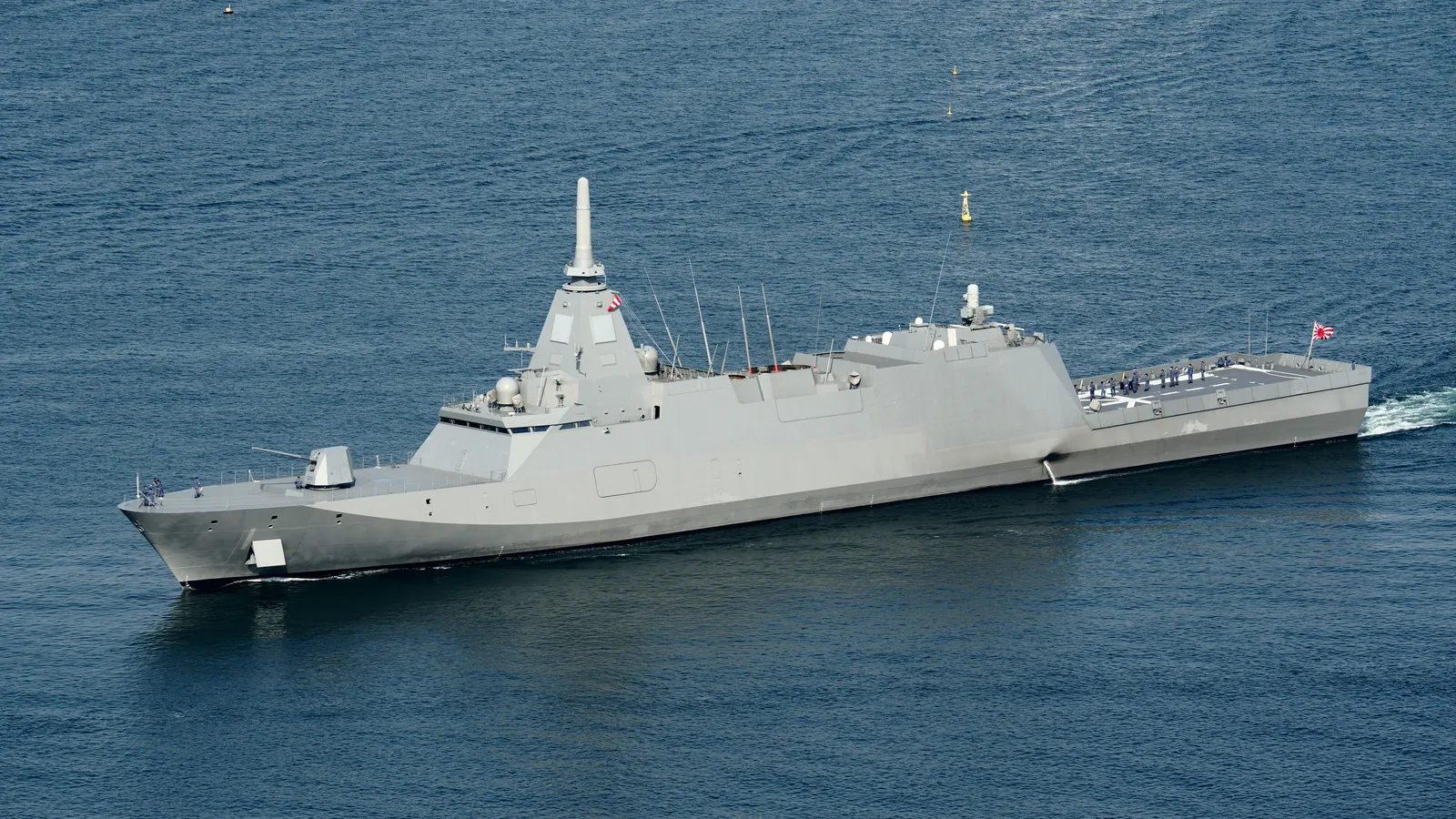 The Japanese frigate JS Mogami (FFM-1) underway at sea, its slender enclosed UNICORN antenna mast rising above the smooth pyramid-shaped stealth superstructure.
